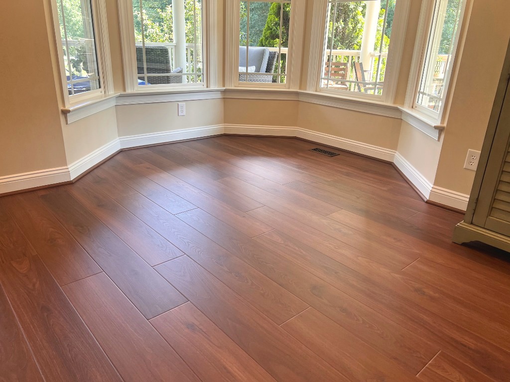 Warm chestnut wide plank hardwood and 5-facet bay window trim by CRG Flooring