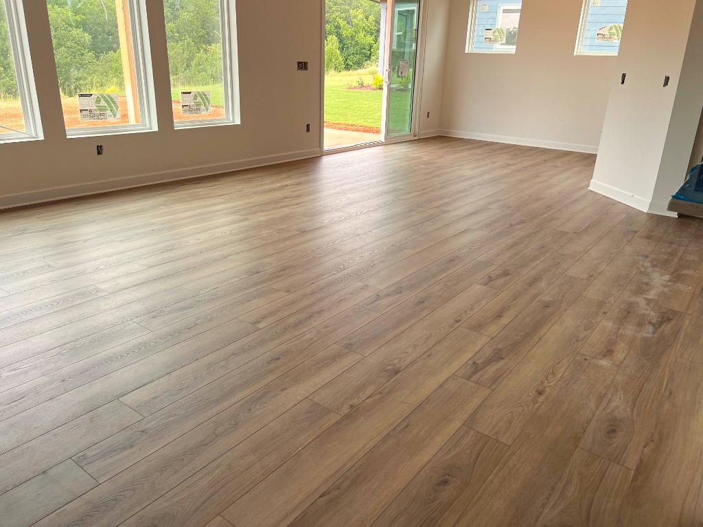 Sunlit open concept wide plank hardwood floor leading to patio by CRG Flooring